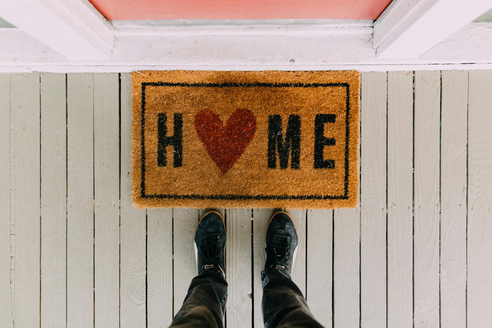 A creative doormat with heart motif symbolizing home at a front porch entrance.